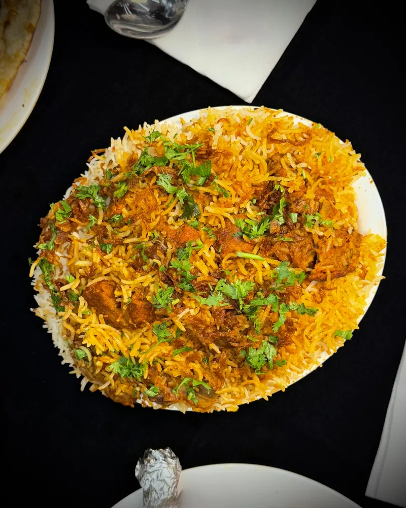 A chicken biryani plate at Madina Hotel, the rice topped with fried onion and fresh coriander