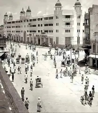 Archival photograph of the Madina Building from further along Pathergatti Road, the street ahead filled with cyclists and pedestrians