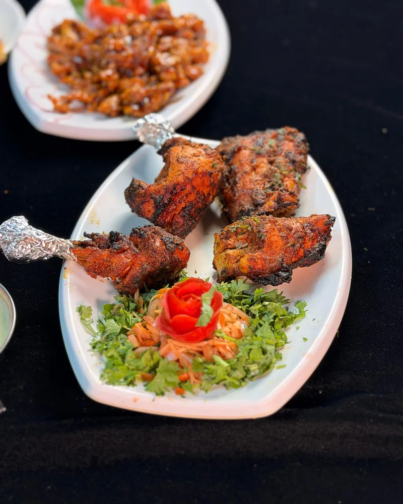 Tandoori chicken quarters, charred at the edges, served over chopped coriander and onion